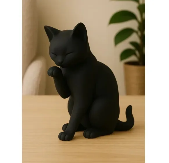 Figura de gato negro lamiéndose la pata, sobre una mesa de madera