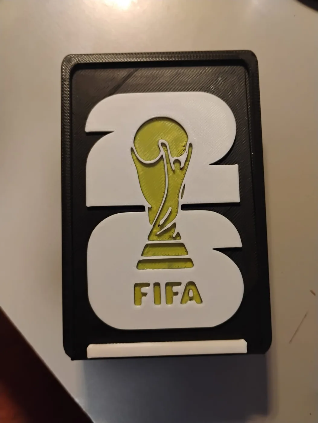 Placa decorativa con el emblema de FIFA 26 y el trofeo en relieve