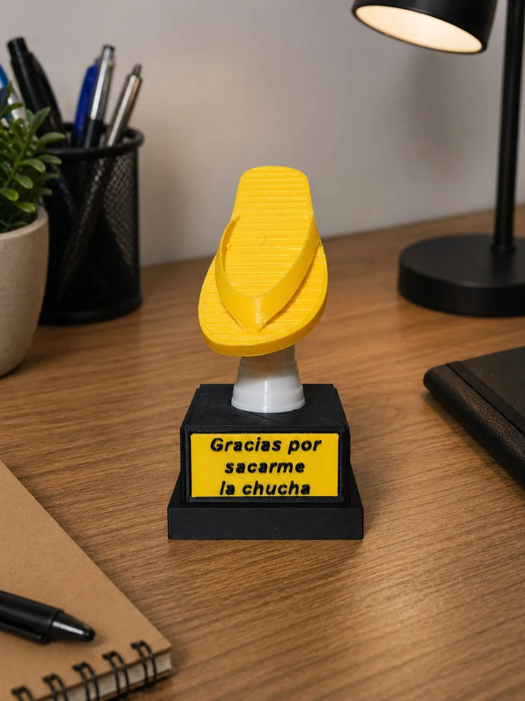 Trofeo con una chala amarilla y una placa con texto grabado